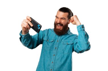 Genç kendinden geçmiş adam az önce kazandığı havalı telefonuyla oynuyor. Kazanan adamın stüdyo çekimi..