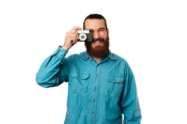 英俊的大胡子男人拿着一架老式相机拍照 透过镜头看 — 图库照片