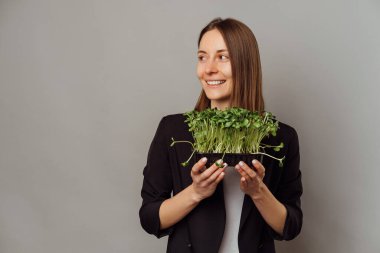 Gülümseyen genç kadın elinde yeşil ayçiçeği lahanalı bir güveç tutuyor. Sağlıklı beslenmeyi seviyorum..