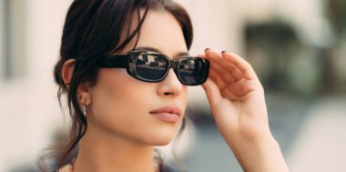 Siyah güneş gözlüğünü takan genç ve ciddi bir kadının mahsul portresini yakından çek..