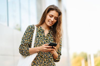 Şehirde akıllı telefonunu kullanan genç bir kadının yakın plan fotoğrafını çek..