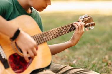 Genç kızın akustik gitar çalarkenki fotoğrafını kapat..