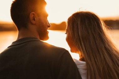 Güzel bir çiftin yakın çekimleri sonbaharda göl kenarında günbatımının keyfini çıkarır..