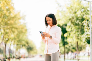 Güzel orta yaşlı kadın sabah dışarı çıkmadan önce telefonunu kontrol ediyor..