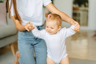 Neşeli kız ilk adımlarını annesiyle birlikte atıyor. Evde yardım ediyor..