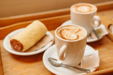 Kafede iki fincan kapuçino ve tatlı kahvaltının fotoğrafını çek..