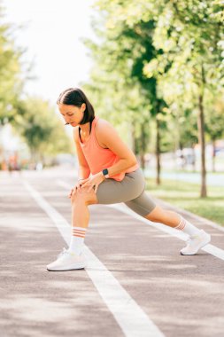 Sporcu kadının maratondan önce bacaklarını dikleştirdiği dikey görüntü.