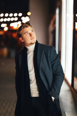 Şehirde geceleri ceketli yakışıklı bir sarışının dikey portresi..