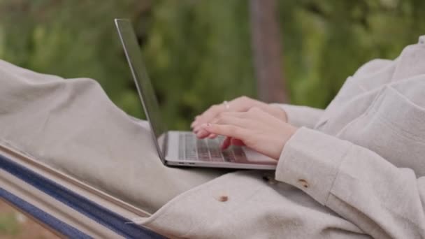 坐在吊床上在笔记本电脑上工作的女性的特写视频 — 图库视频影像