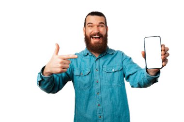 Mavi tişörtlü bir adam cep telefonuna boş ekranla bakıyor. Beyaz arkaplanda stüdyo görüntüsü.