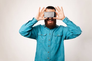 Heyecanlı sakallı adam gözlerini fotokopi cihazıyla kapatıyor. Stüdyo çekimi.