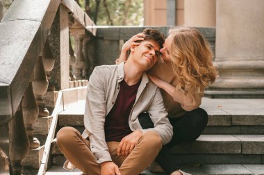 Aşkta neşeli çift merdivenlerde otururken birlikte vakit geçiriyor..