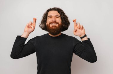 Genç yakışıklı sakallı adam dileği için dua ediyor. Stüdyo portresi gri arkaplan üzerinde.