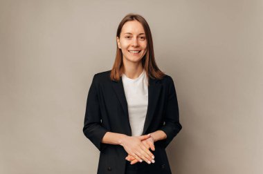 Siyah ceket giyen akıllı kadın kameraya gülümsüyor..