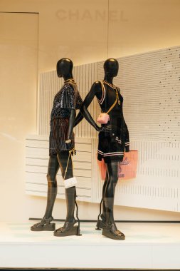 21 Şubat 2023, İspanya, Barselona. Barcelona 'daki mağazada Chanel logosu yakınında duran iki siyah mankenin dikey çekimi..