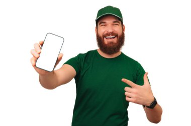 Elinde tuttuğu boş bir telefon ekranına yeşil üniformalı mutlu sakallı adam..