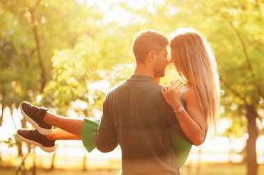 Açık havada, aşık bir gencin yazın günbatımında kadınını kucağında tutarken çekilmiş..