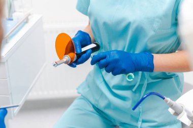 Kadın bir dişçinin kablosuz ultraviyole lamba tutarken yakın plan fotoğrafı..