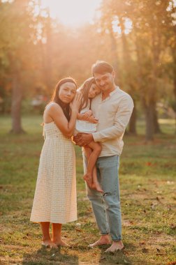 Günbatımında bir anne, baba ve kızının güzel dikey aile portresi..