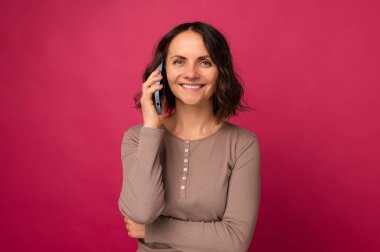 Yakışıklı, gülümseyen orta yaşlı kadın telefonda hoş bir konuşma yapıyor..