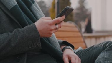 Parktaki bankta oturan ve akıllı telefonunu kullanan adamın videosunu kapat..