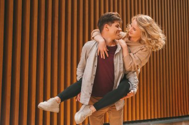 Neşeli genç adam güneşli bir günde kız arkadaşını sırtında taşıyor..