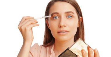 Beyaz arka plan üzerinde ayna ve göz farı tutan genç bir kadının afiş boyutunda fotoğrafı..