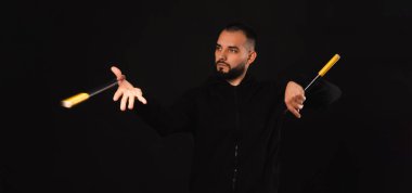 Ciddi bir gencin afiş portresi siyah arkaplan üzerinde nunchaku sanatında ustalaşıyor..