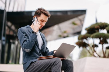 Kendine güvenen bir gencin açık hava portresi. Birini ararken uzaktan çalışıyor..