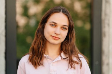 Güneşli bir günde açık havada gülümseyen genç bir kız öğrencinin açık hava portresini kapatın..