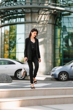 Merdivenlerden inen takım elbiseli genç bir kadının dikey portresi..