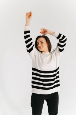 Gözleri kapalı dans ederken eğlenen neşeli genç bir kadının stüdyo portresi..