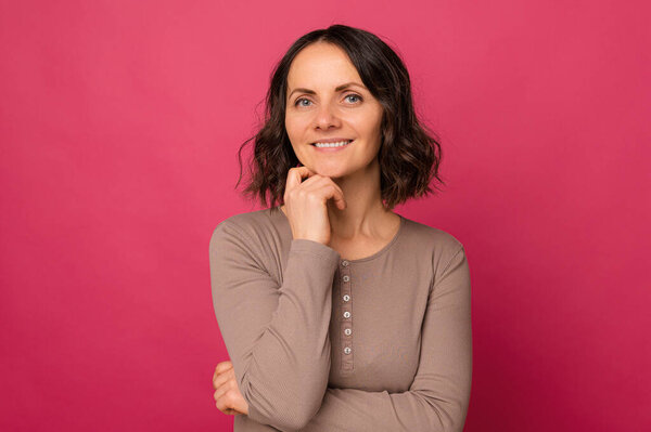 Студийный портрет красивой зрелой широко улыбающейся женщины на розовом фоне.