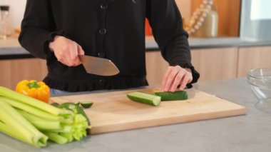 Taze salata için mutfakta salatalık doğrayan kadının videosunu kapat..