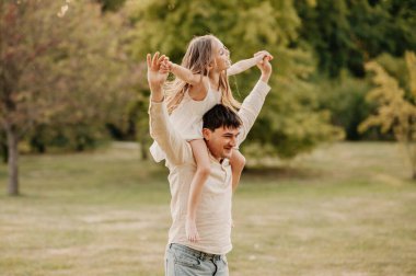 Babacığın parkta oynarken kızını omuzlarında taşıyor..