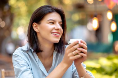 Gülümseyen genç bir kadının yazın parkta sabah kahvesinin tadını çıkarırken yakın plan çekimleri..