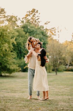 Üç kişilik çıplak ayaklı genç bir aile parkta güzel vakit geçiriyorlar..