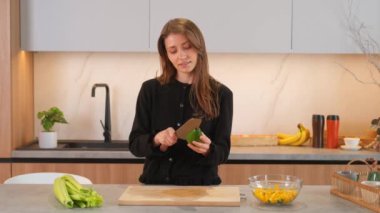 Genç beyaz kadın sağlıklı ve lezzetli salata için avokado kesiyor..