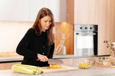 Genç, kendine güveni tam bir kadın mutfakta sağlıklı sebzeleri kesiyor..