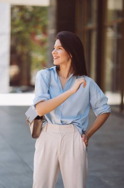 Güneşli bir günde şehrin dışında gülümseyen genç bir kadının dikey portresi..