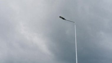 Tek sokak lambası bulutlu ve bulutlu bir gökyüzünün arka planında duruyor. Minimalist ve yalnız sahne.