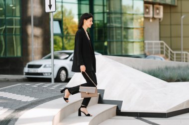 Şık giyimli iş kadını modern şehirde şehir mimarisi ile merdivenleri çıkıyor..