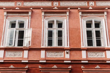 Pembe, tarihi bir Avrupa binasının üç kemerli penceresi ve karmaşık tasarımları olan ön cephesine yakın plan.