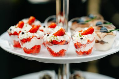 Çileklerle süslenmiş lezzetli çilek ve kremalı tatlı fincanları. Etkinlikler ve kutlamalar için mükemmel..