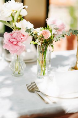 Göz kamaştırıcı bir masa üstü açık pembe güller ve şakayıklarla süslenir. Zarif bir çatal bıçakla zarif bir dekor oluşturulur.