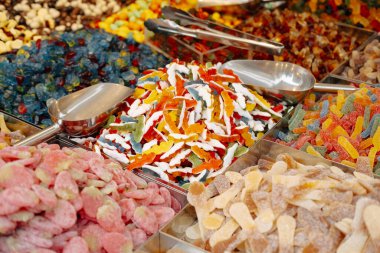 Yakın çekimde piyasada çeşitli renklerde şekerler sergileniyor, çeşitliliklerini ve canlılıklarını yansıtıyor.