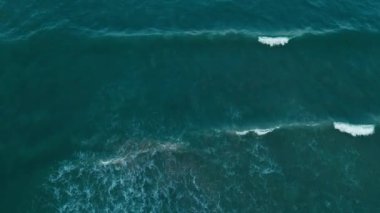 Alacakaranlıkta yukarıdan görülen sakin okyanus dingin dalgaları ve denizin barışçıl doğasını gösteriyor.