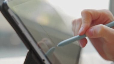 Bir tablette stil kullanarak dijital sanat yaratma sanatını sergilerken ustalıkla bir elin detaylı bir yakın çekimi.