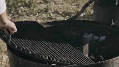 Eller ızgarayı sıcak kömürlerin üzerine ustalıkla yerleştiriyor, etkileyici barbekü hazırlama becerileri sergiliyor.