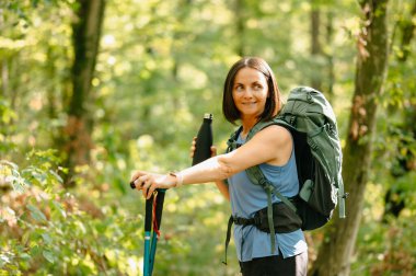 Bir kadın, canlı bir orman zeminine karşı doğa yürüyüşünün keyfini çıkarırken görülüyor.